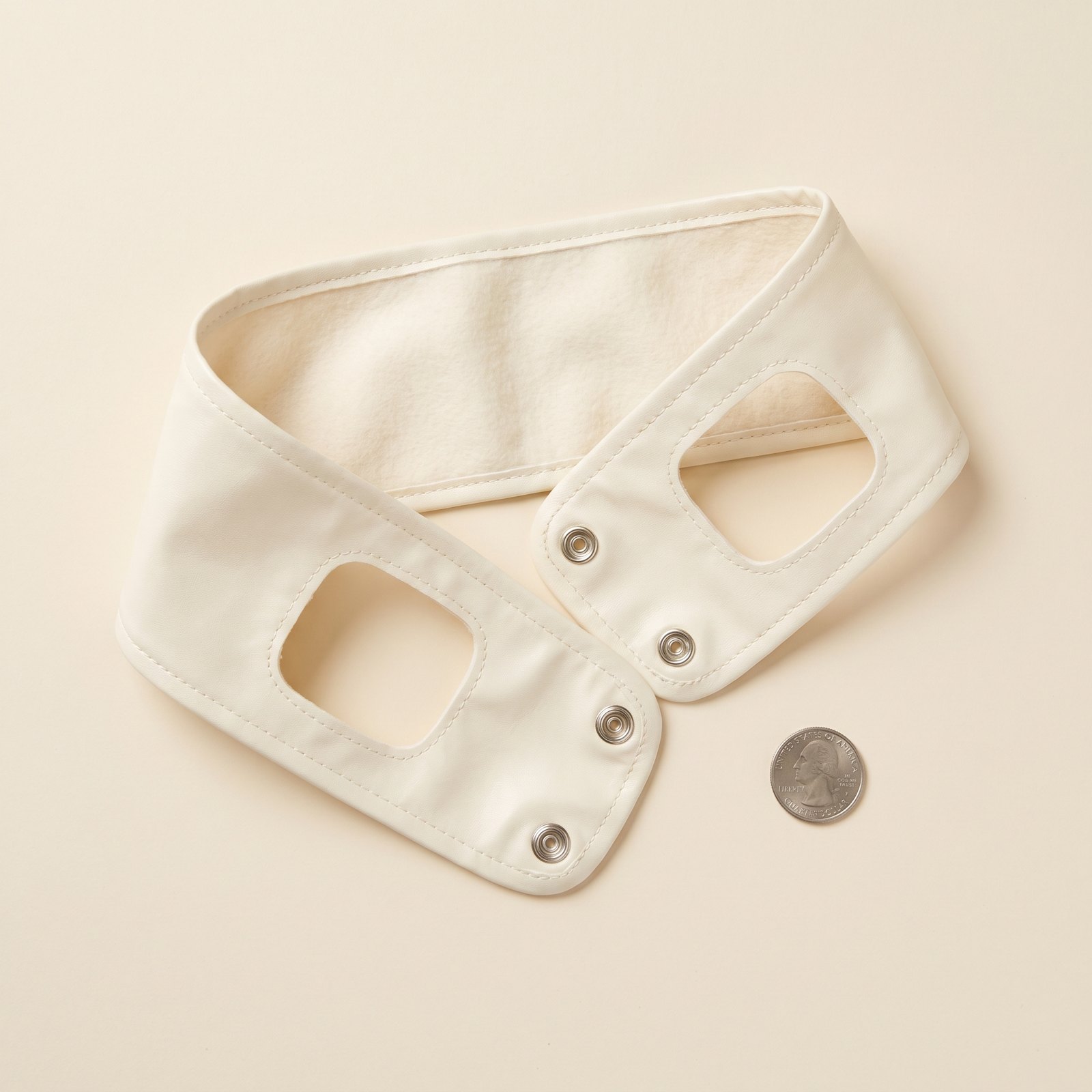 Cream fabric cat headband, lying open, with two ear apertures and metal snap studs