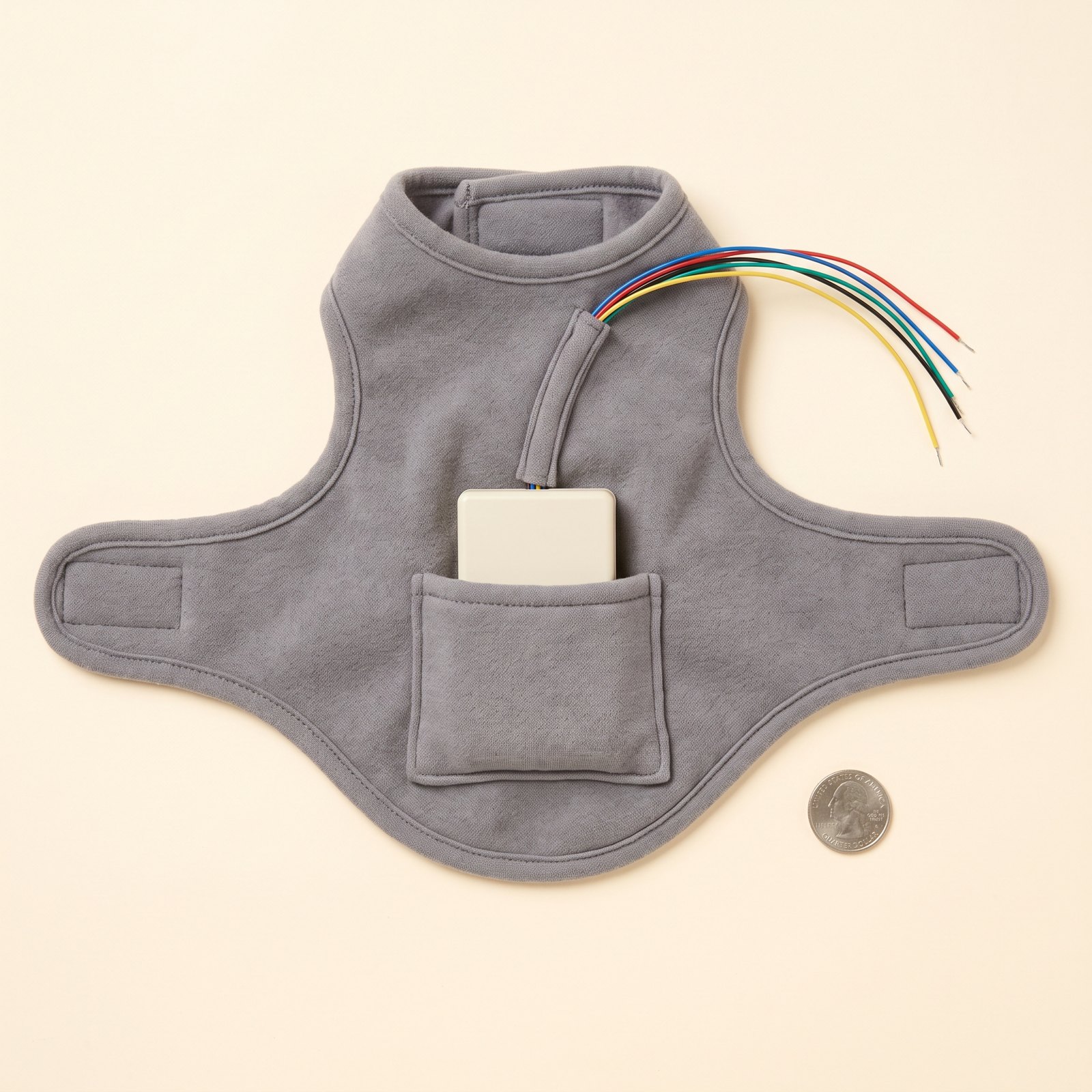 Grey fabric vest with the board enclosure in a back pocket and colour-coded leads exiting a channel